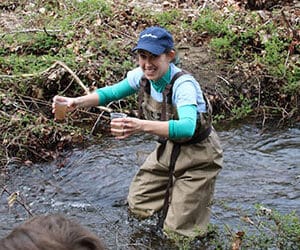 Science teacher releasing salmon into river