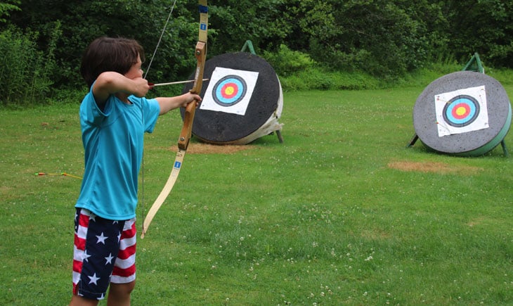 Boy shooting arrow in archery class