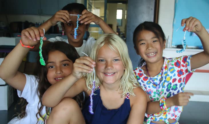 Four girls holding up bracelets they made