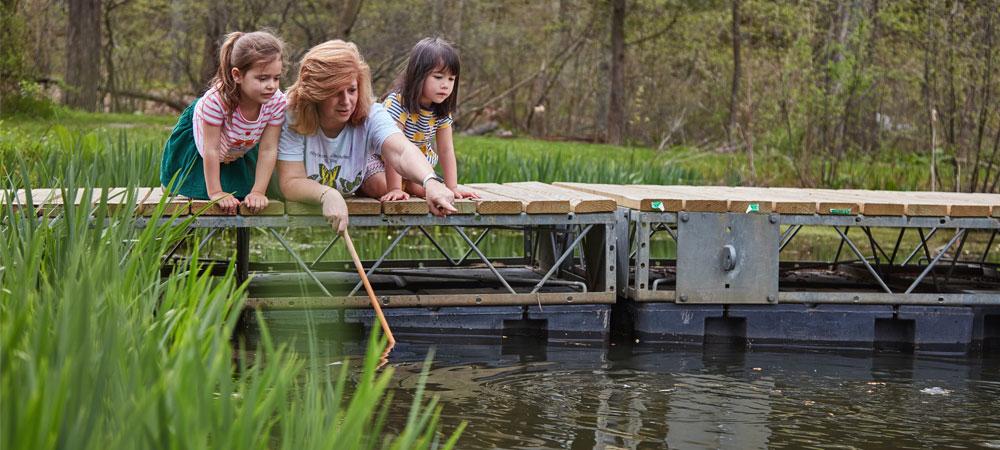 Counselor and 2 girls on dock at pond