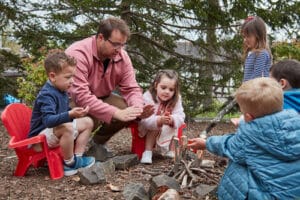 Preschool children and teachers warming hands over a pretend campfire