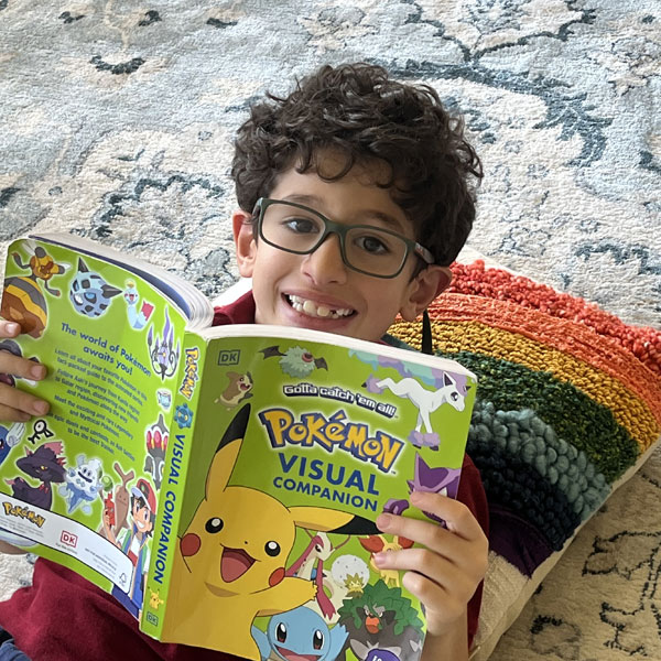 boy laying on rug reading Pokemon book