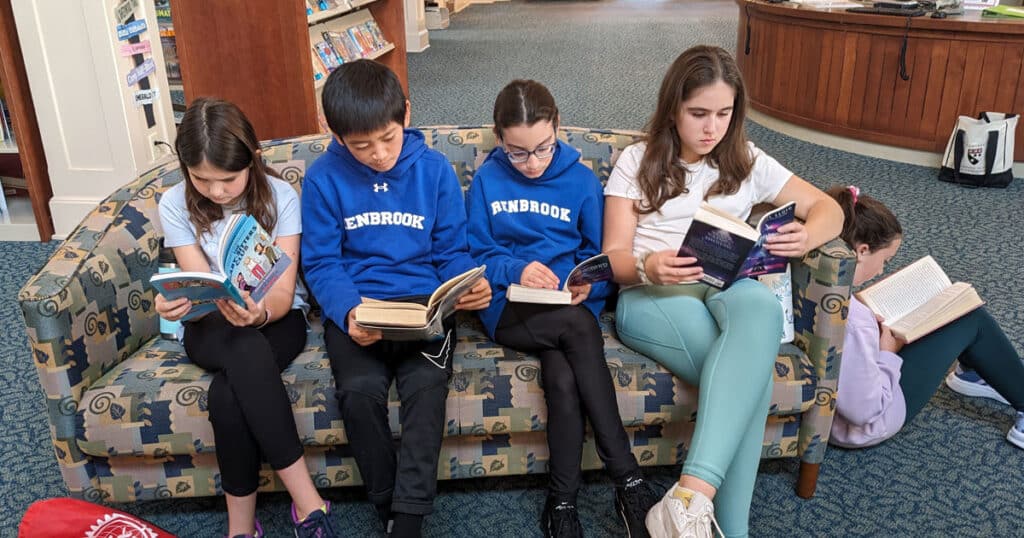 3 girls and 2 boys reading on couch in library