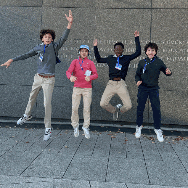 Four pre-teenage boys jumping in front of a wall