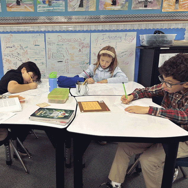 Three students doing research at a cluster of desks