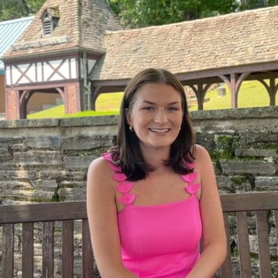 Photo of alumna Catherine Daniels sitting on bench in pink dress